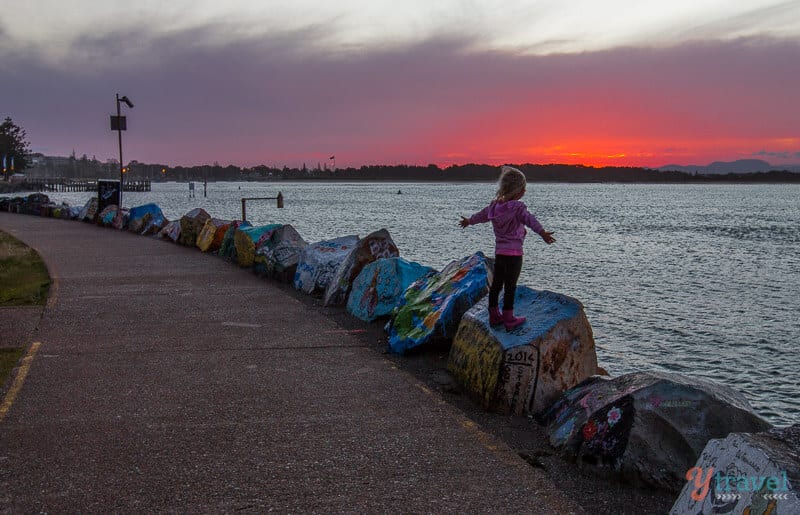 girl standing on breakwall at Sunset