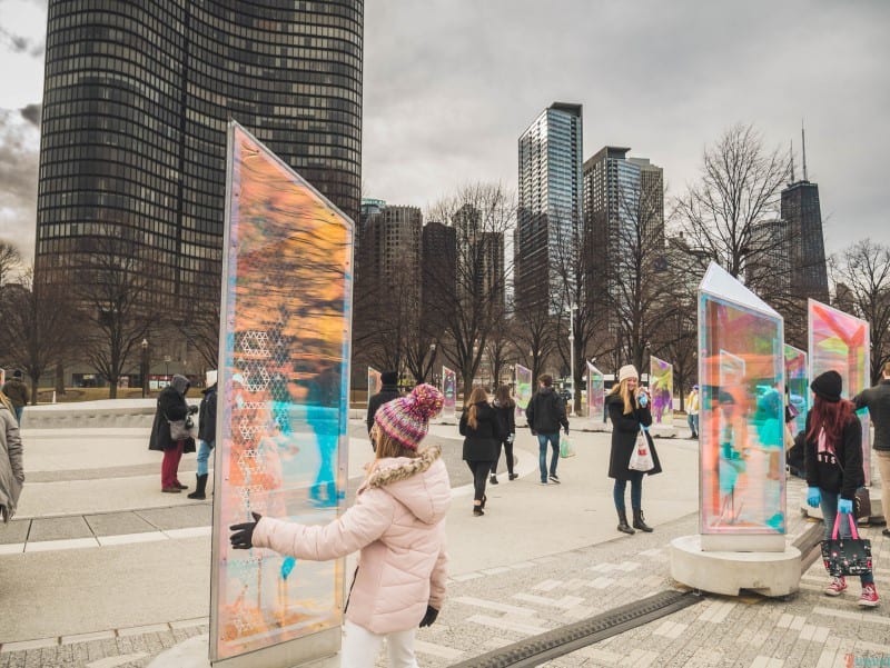 girl looking into colored glass reflection at Prismatica Art installation Polk Park 