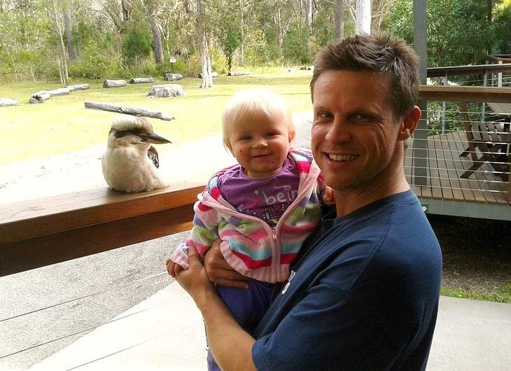 a man holding a child next to a zoo exhibit