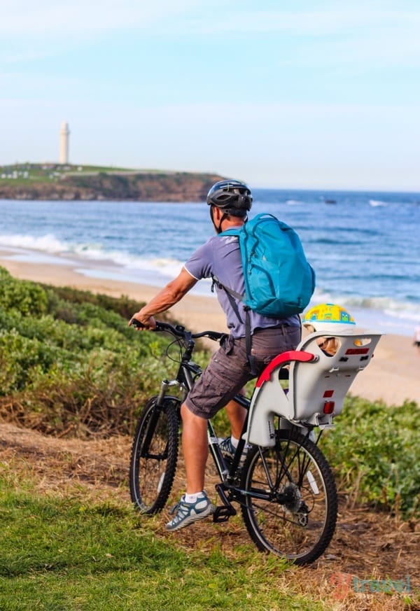 man riding along beach with child in the back