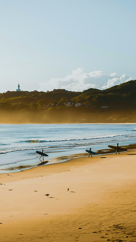 Surfers catching morning waves at Belongil Beach, Byron Bay