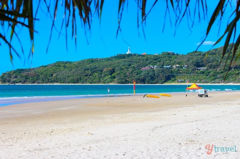 lifesaver umbrella and boards on beach with byron lighthouse in background