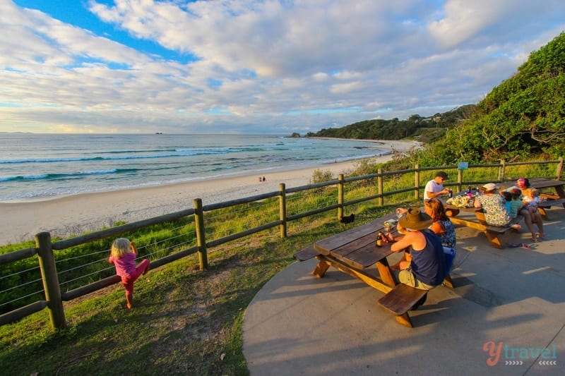 [people sitting at picnic tables looking at the beach