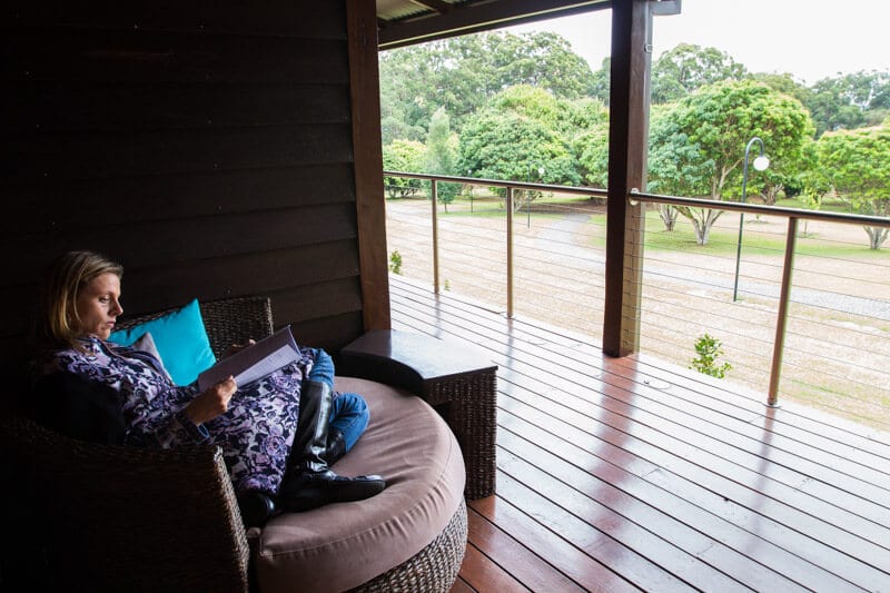 woman sitting on chair on villa deck reading