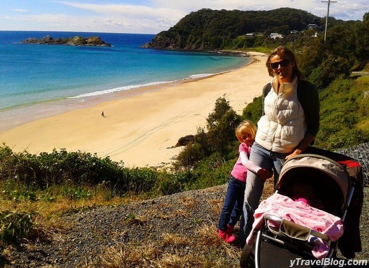 a woman hiking on a trail next to a beach with her children