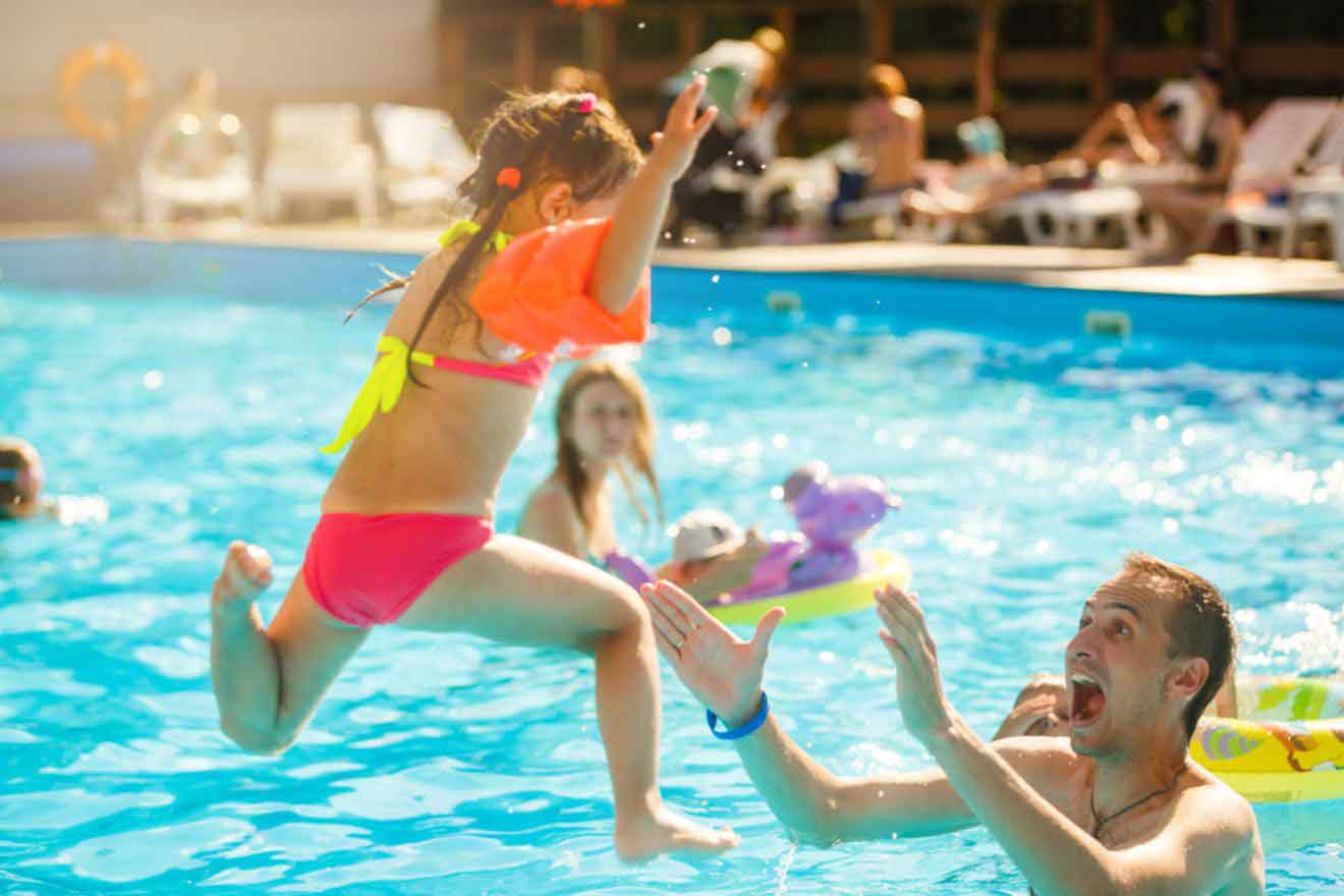 girl having fun in the pool with her dad