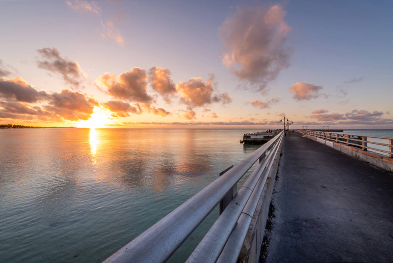 the sun sets on the horizon of the atlantic ocean and the pier