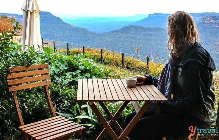 woman drinking tea at table looking at view of the Blue Mountains