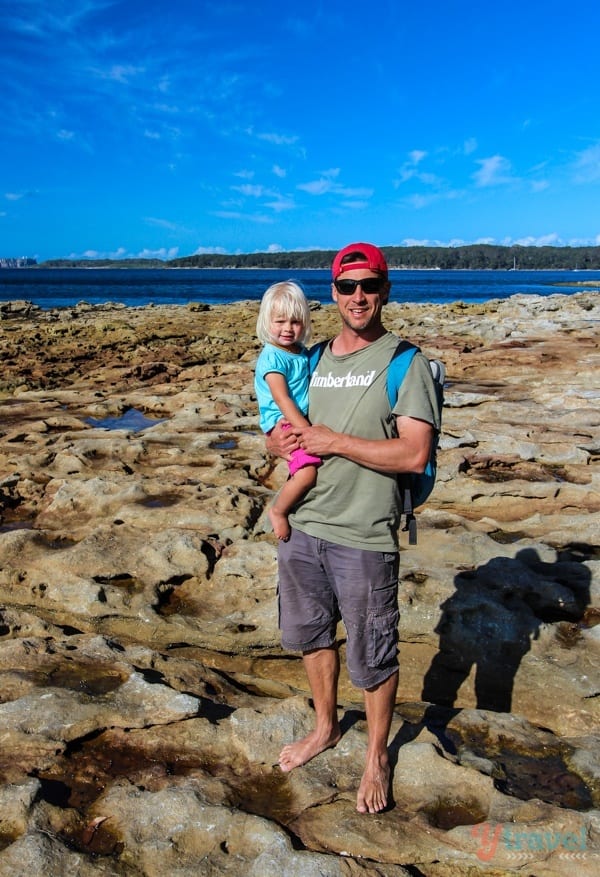 a man holding a child while standing on rocks