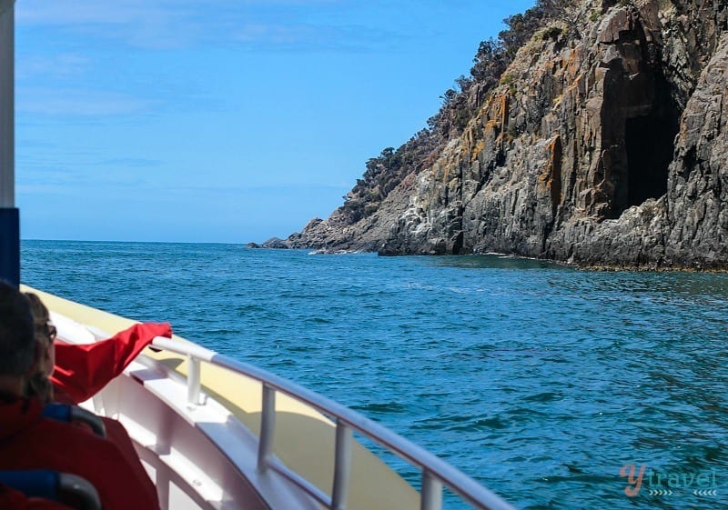 a boat on water next to a cliff