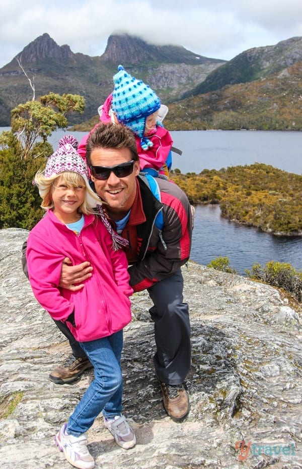 a man holdings kids while standing on a rock