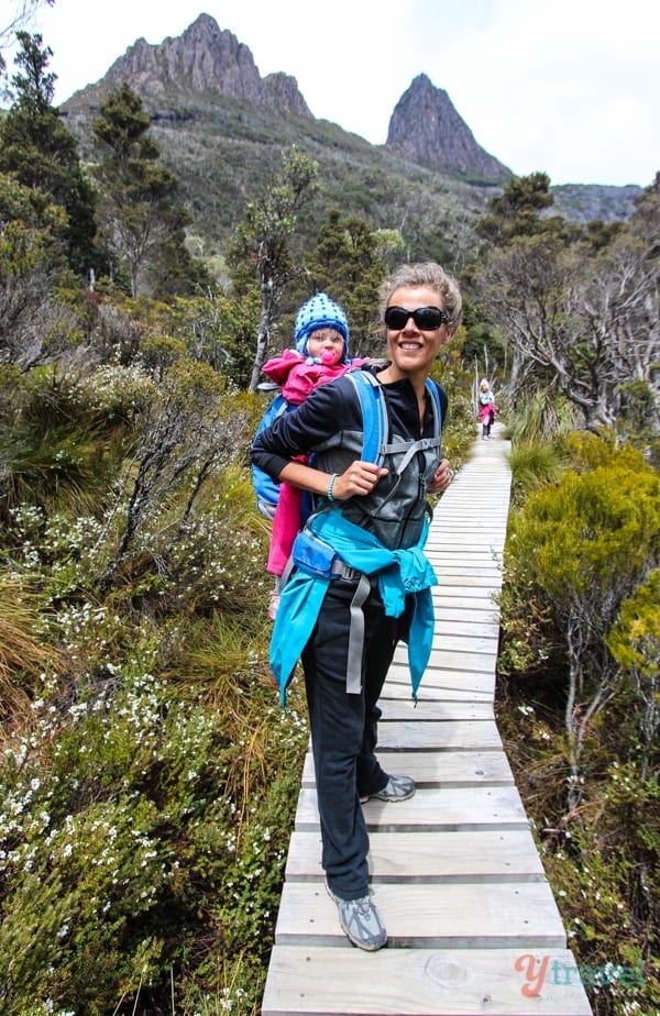 woman carrying a baby while walking on a boardwalk