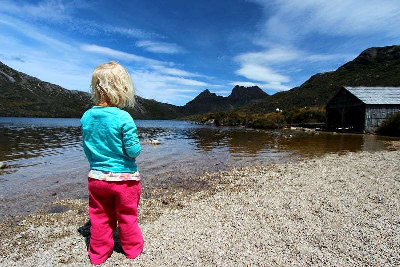 A little girl standing next to a lake