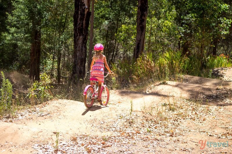 girl bike riding through a forest