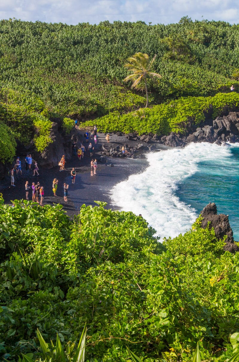 people standing on the Black Sand Beach (Pai’iloa Beach) 