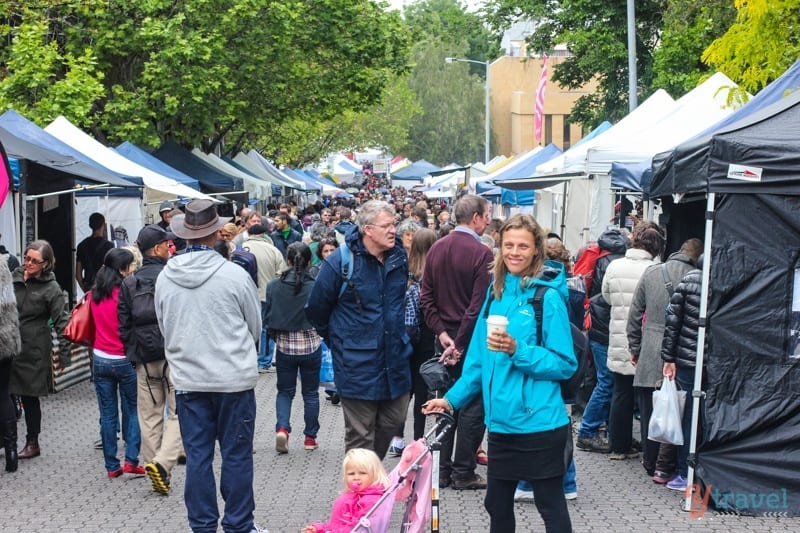 woman holding coffee with stroller in crowded market