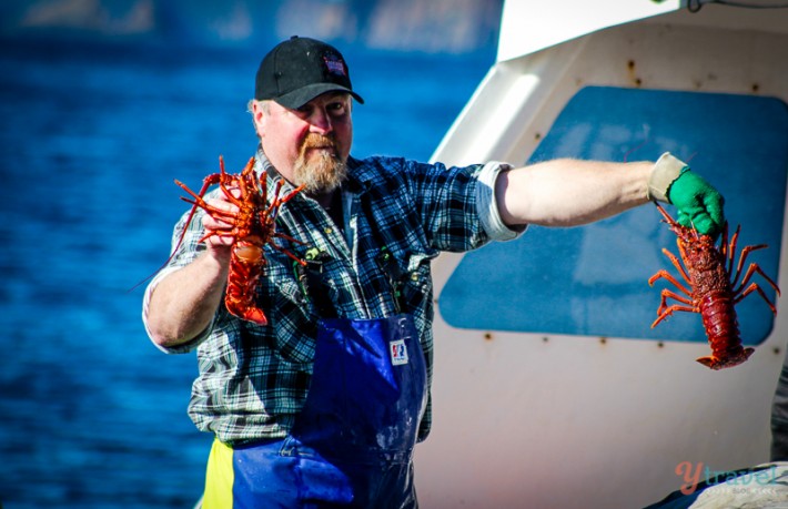 man holding lobster in each hand on fishing boat