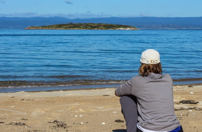 woman sitting on beach looking at water