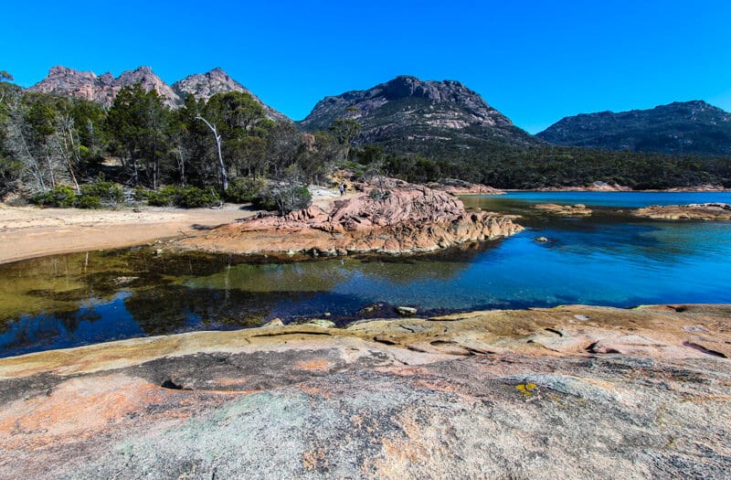 colorful rocks and water with hazard peaks in background at Honeymoon Bay - 