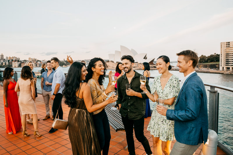 Friends enjoying rooftop drinks in The Rocks with views of Sydney Harbour.