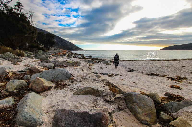 woman walking on beach of Wineglass Bay at sunrise