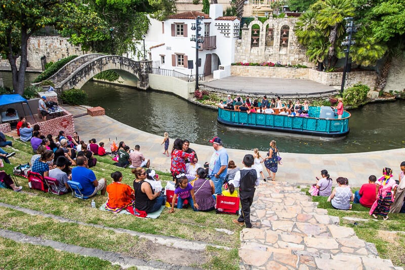 people sittong seats at the Arneson River Theater besie the river