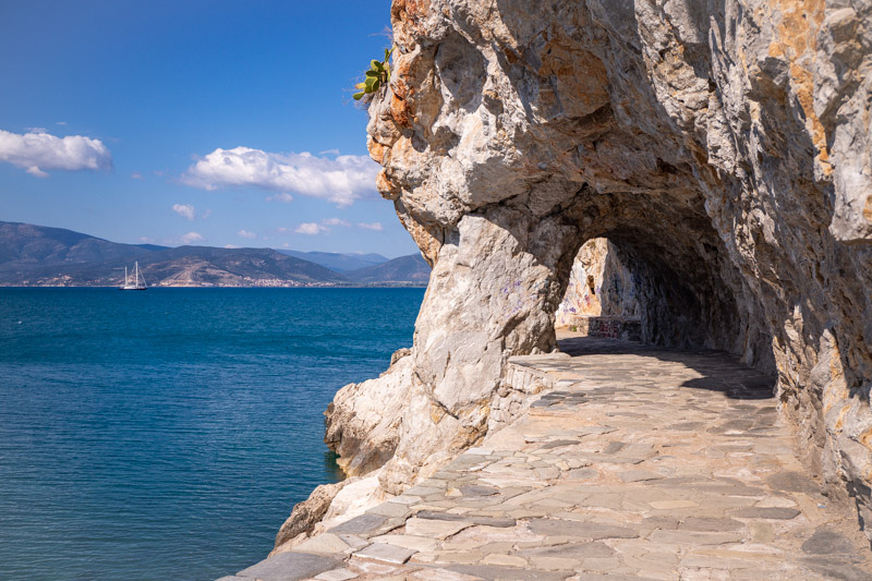 stone pathway going under archway with views of sea