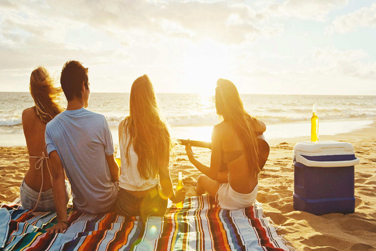 group of friends on the beach singing and watching the sunset