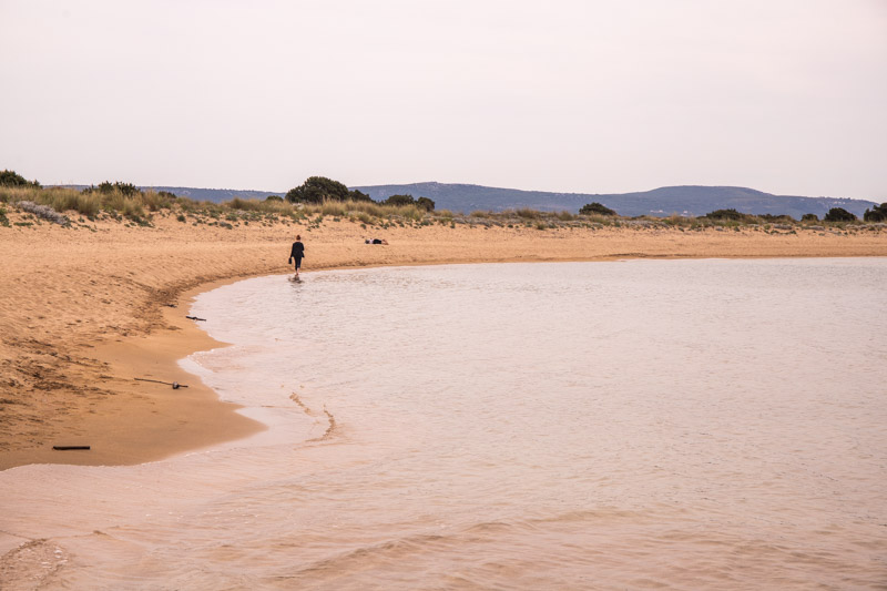 person walking along Voidokilia Beach