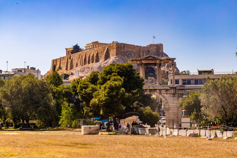 view of acropolis with arch of hardrian in front of the ground and lots of trees