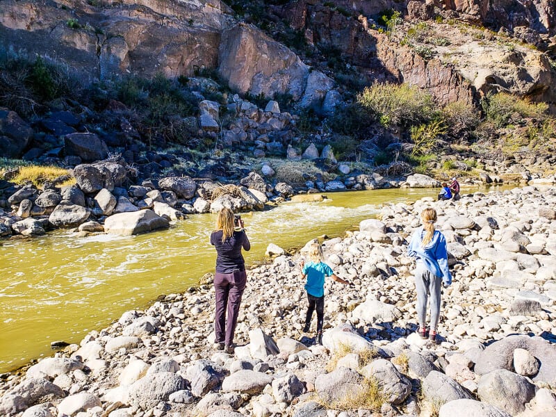 people walking on rocks next to a river