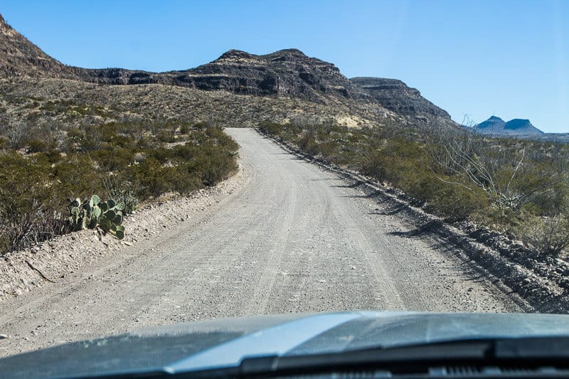 car driving down gravel road in desert