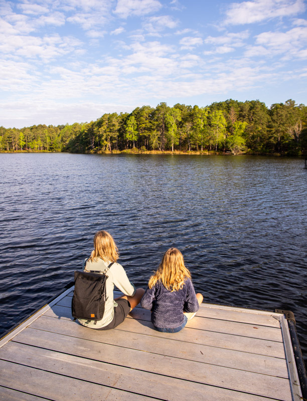 woman and child sitting on edge of lake