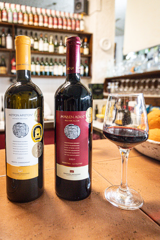 bottle of red and white wine on table with glass of red beside