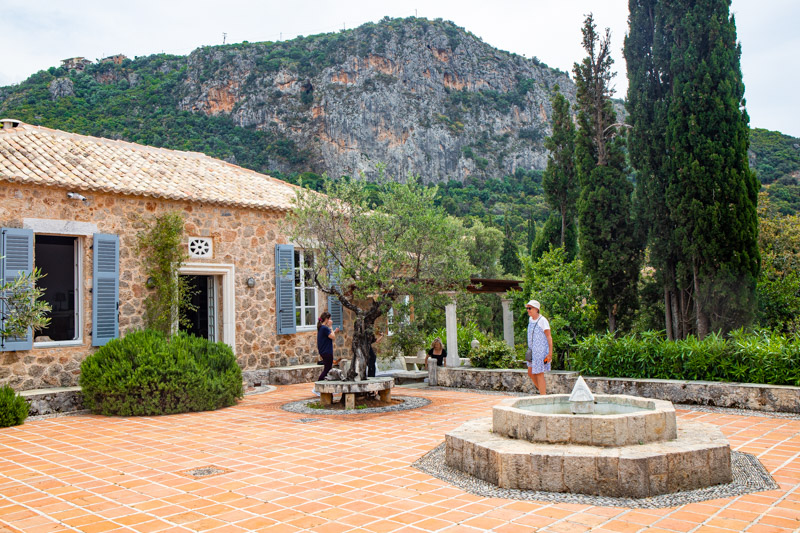 stone villa with fountain in the front courtyard and cypress tress