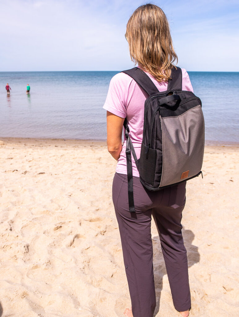 woman standing on beach with driibe backpack on