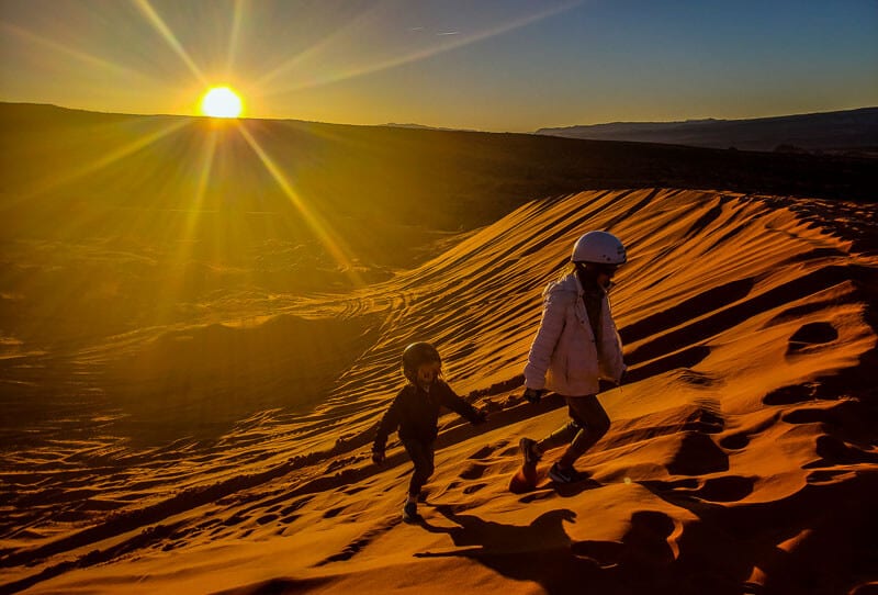 kids walking up sand dunes at sunset at Sand Hollow State Park, Utah