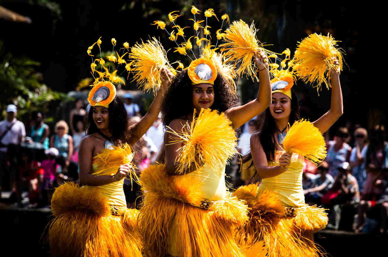 Three women in traditional wear dancing at a luau