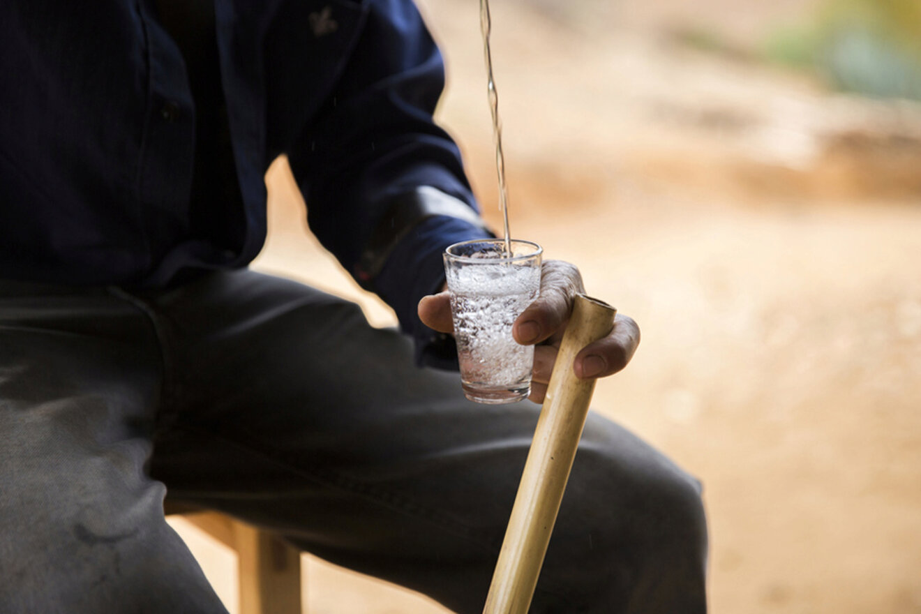 A person pouring mezcal in a shotglass