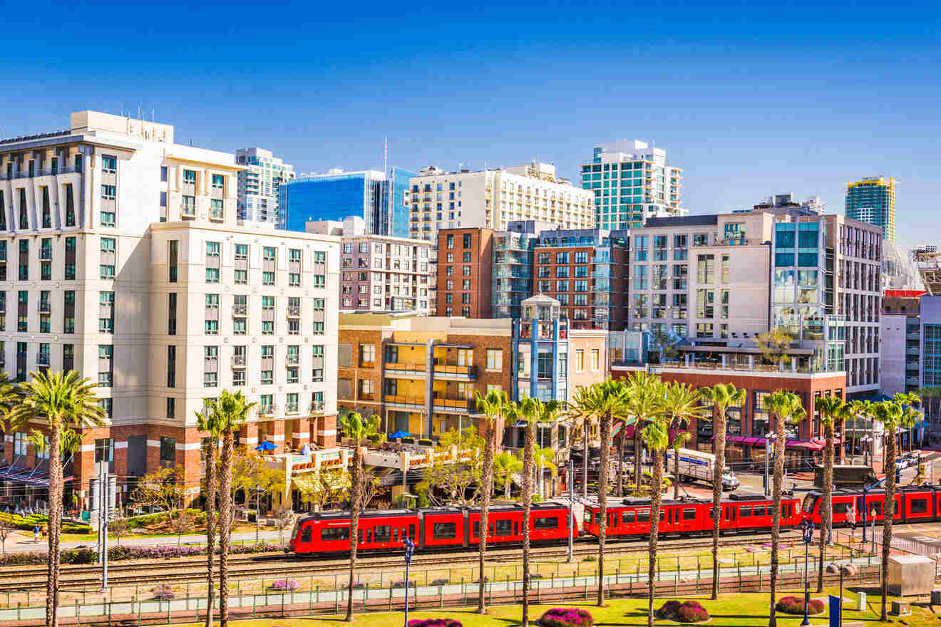 a red train traveling through a city next to tall buildings