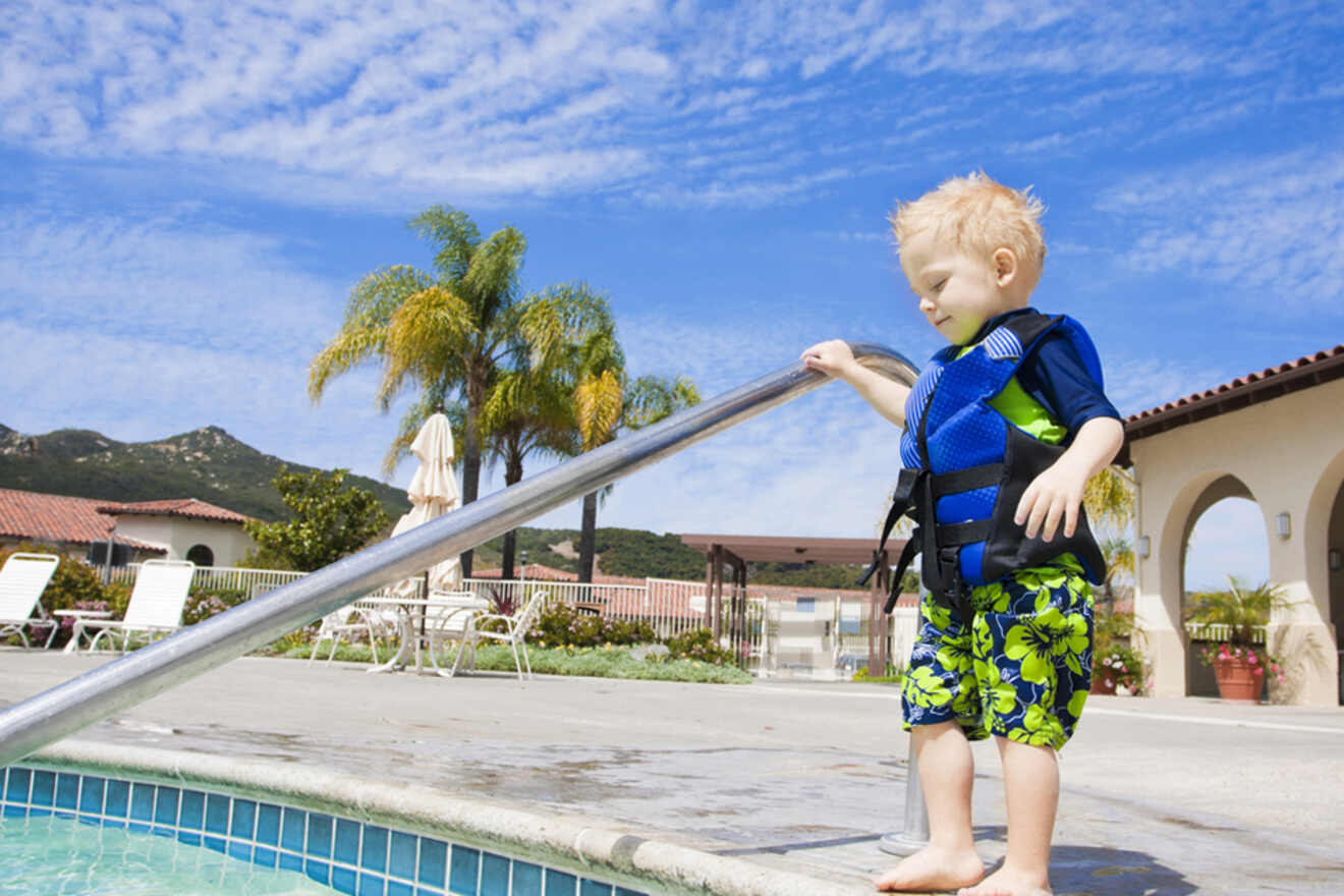 A kid in a life jacket next to a pool