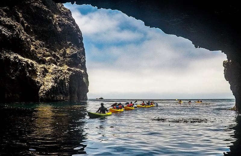 people kayaking next to cliffs