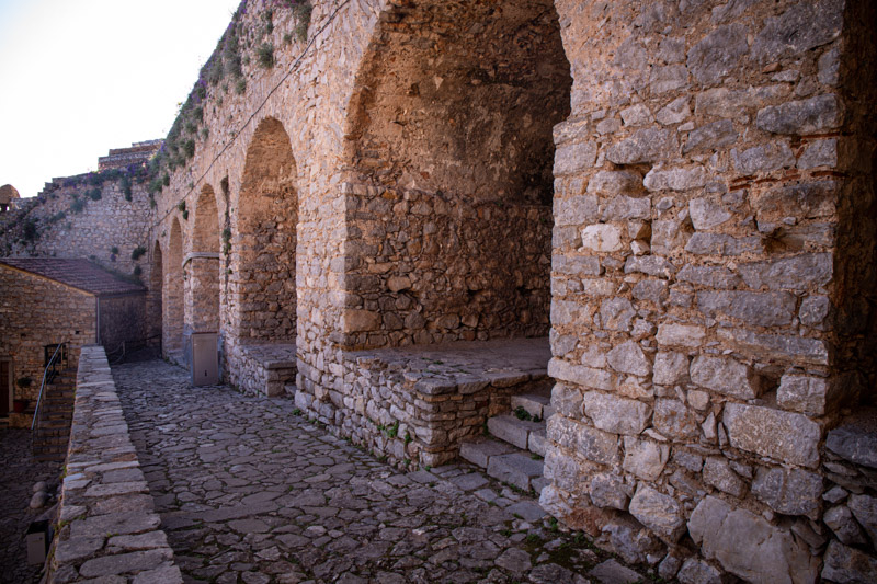 arches in stone wall with small church at end