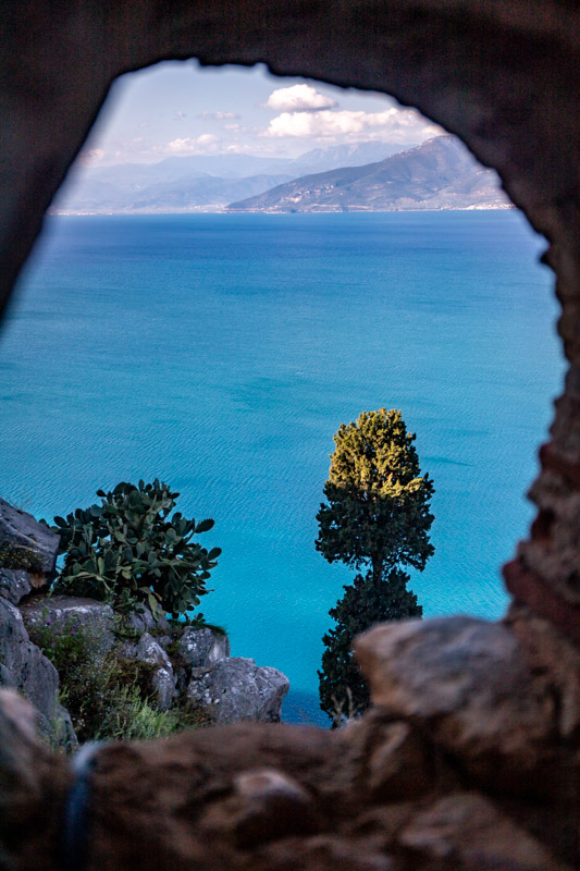 view of sea through a hole in a brick wall