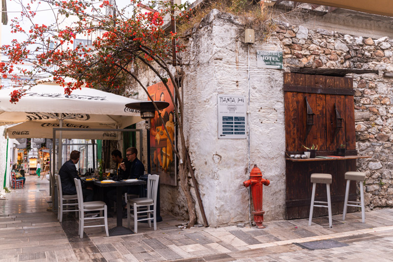 people sitting in alleyway beside white wall building of restuarant