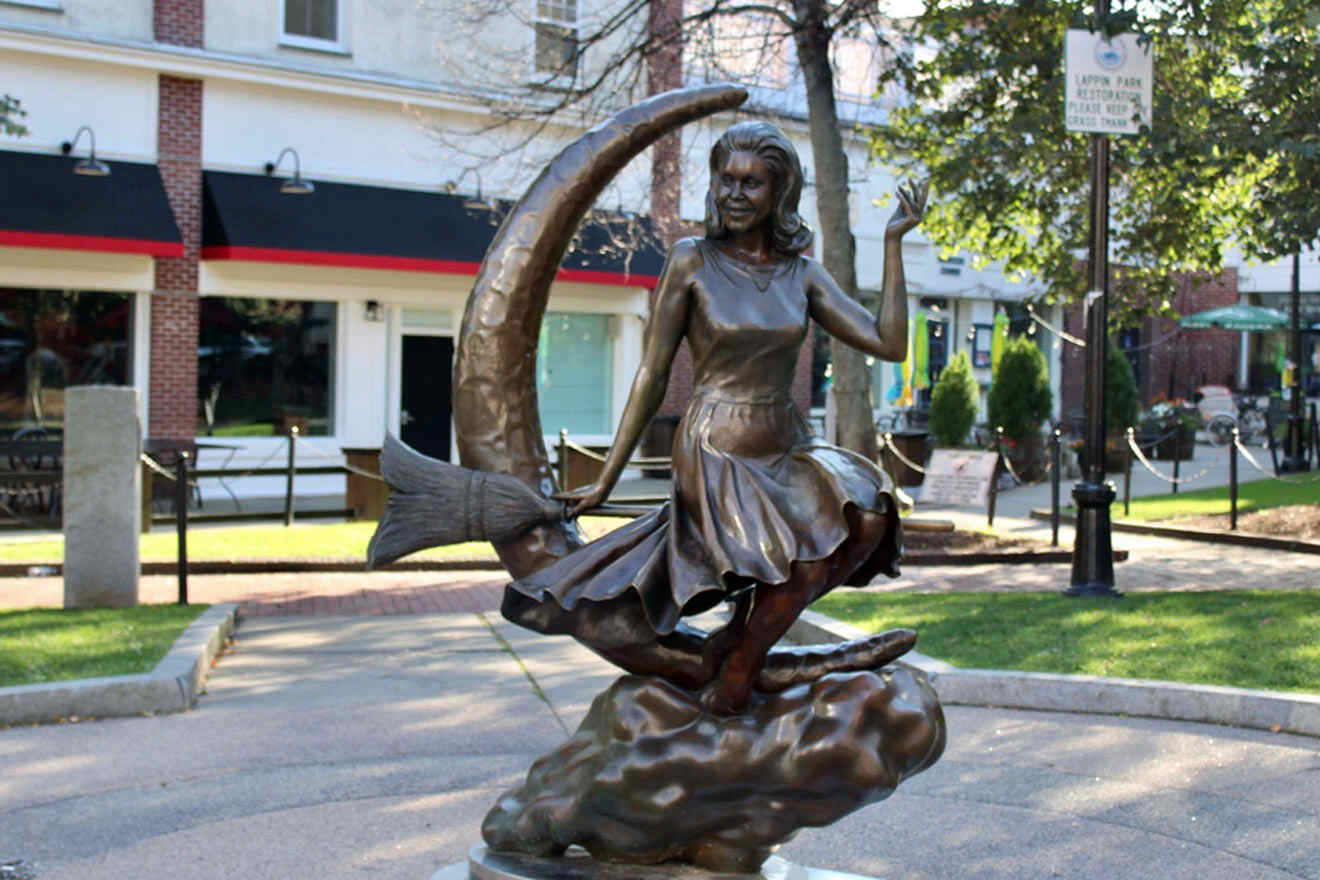 a bronze statue of a witch standing on a broom