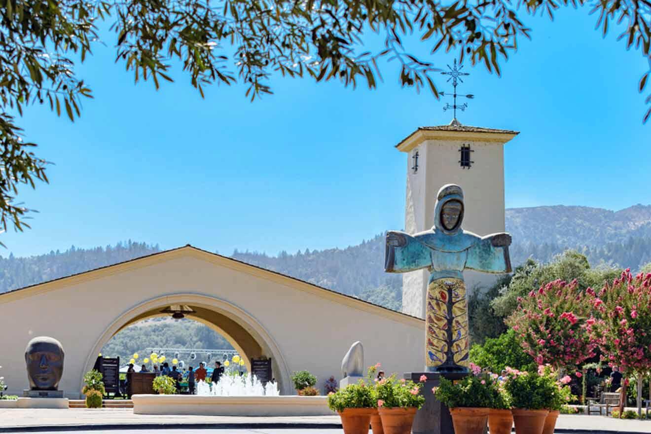 a white building with a tower in the background and a statue with flowers in front of it