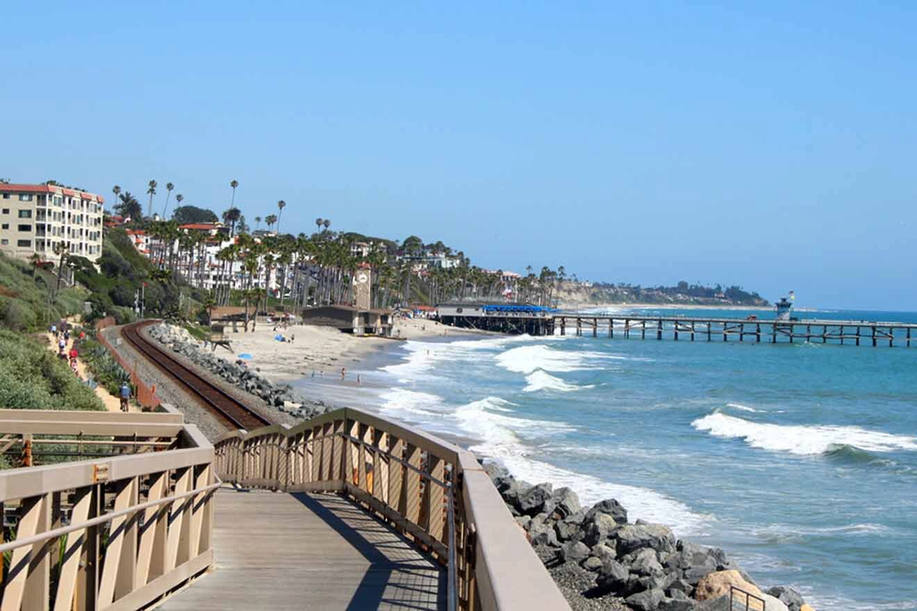 a boardwalk next to the ocean with a pier in the background