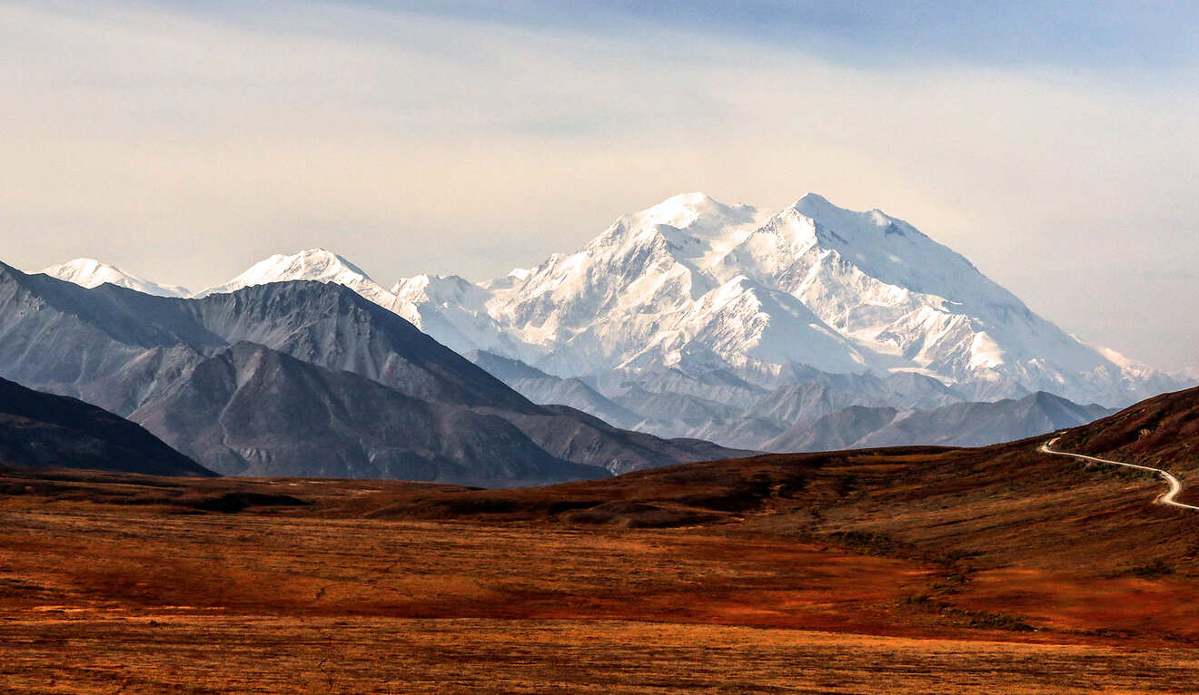 a mountain range with a winding road in the foreground