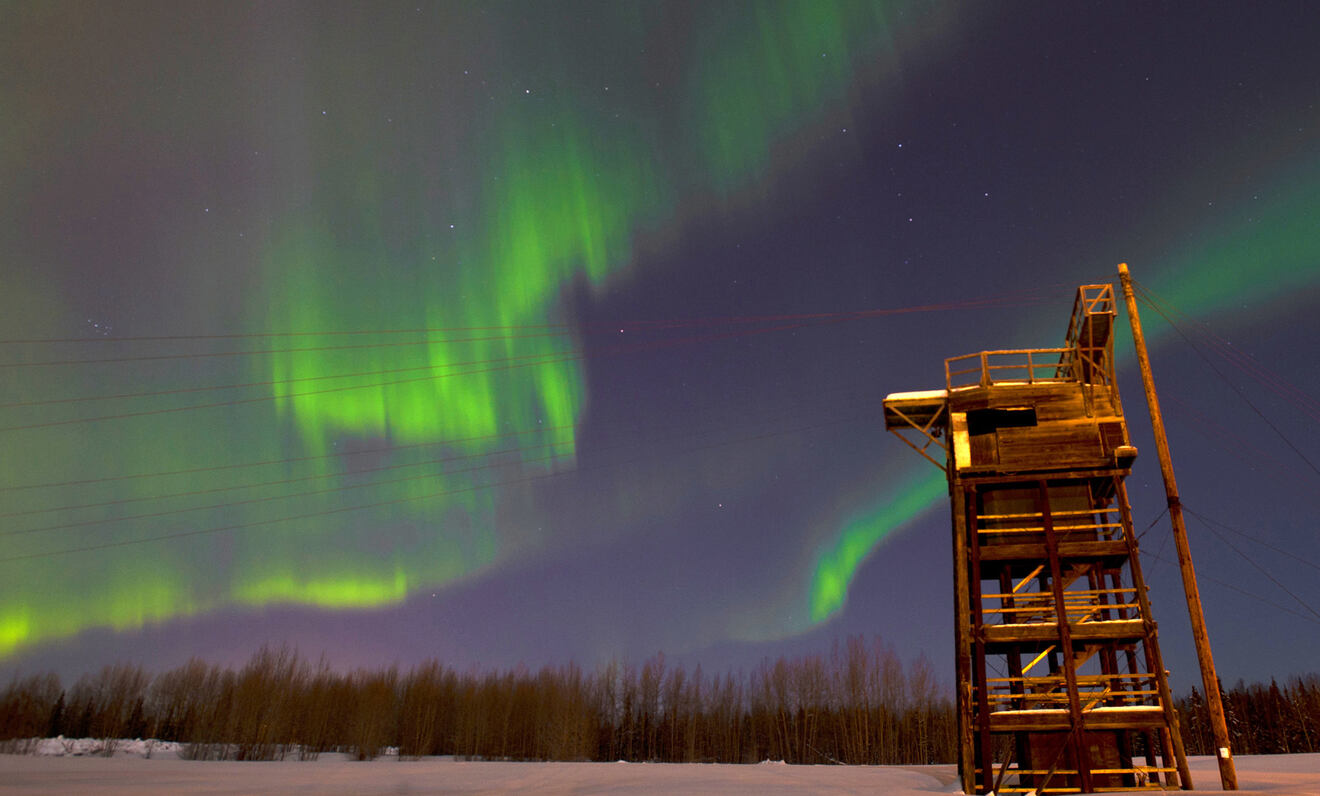 a wooden structure with a ladder under a green and purple sky